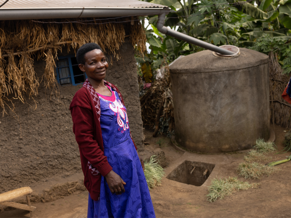 Rwandan woman with a household rainwater tank