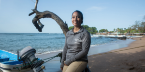Ani Henríquez, Executive Director of ProCosta, leans against a tree and smiles